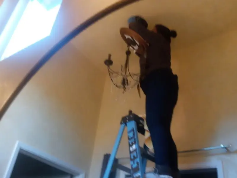 Electrician installing a chandelier in a Polk City residence